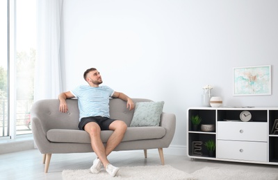 Photo of Young man relaxing under air conditioner at home