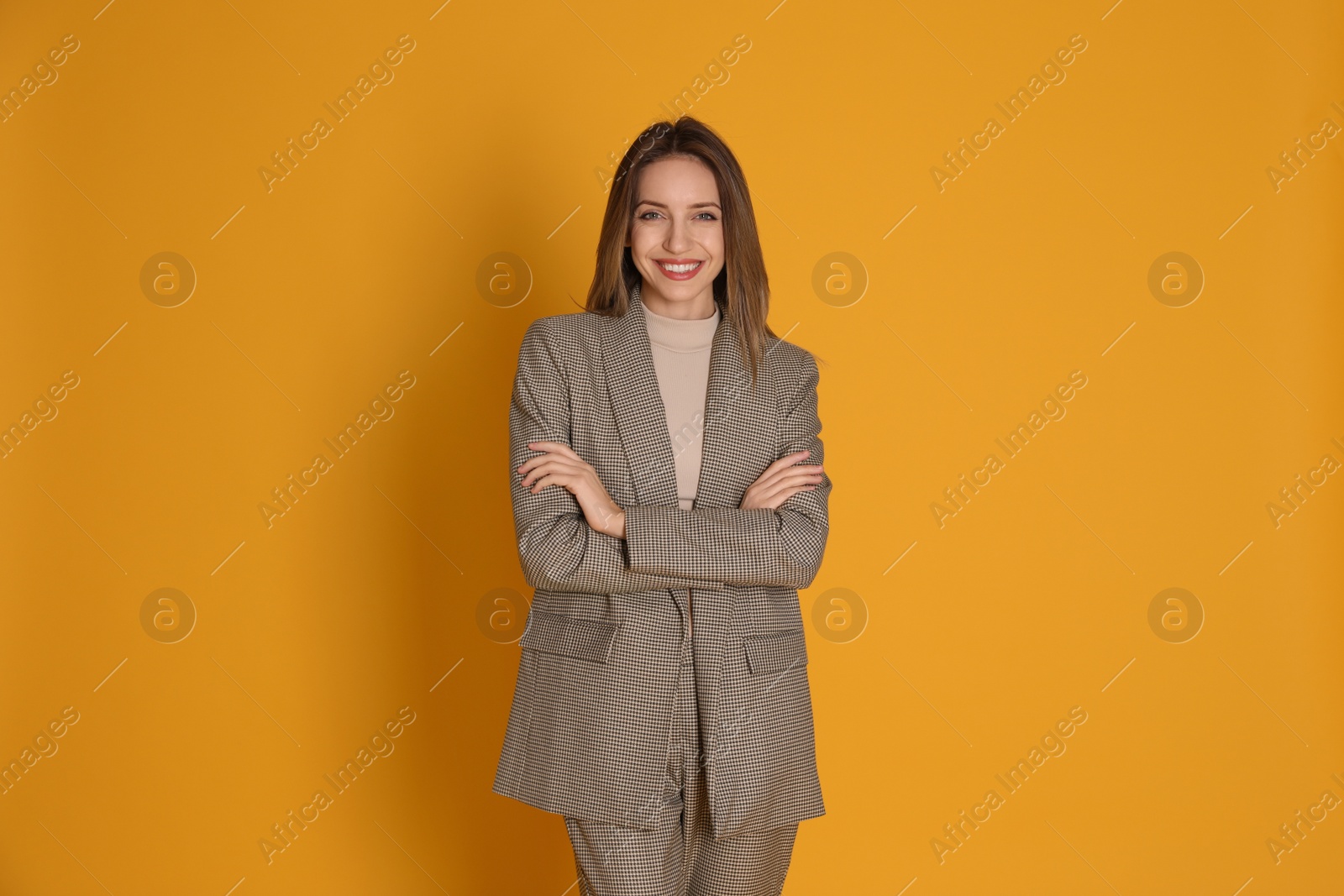 Photo of Portrait of beautiful young woman in fashionable suit on yellow background. Business attire