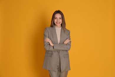 Photo of Portrait of beautiful young woman in fashionable suit on yellow background. Business attire