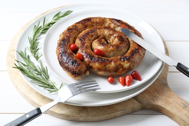Photo of Tasty homemade sausages with peppers and rosemary served on white wooden table, closeup