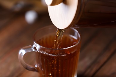 Photo of Pouring delicious tea into glass cup on blurred background, closeup