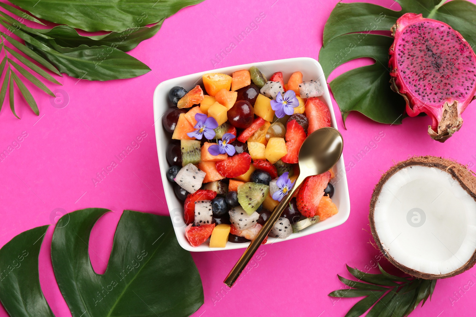 Photo of Flat lay composition with delicious exotic fruit salad on pink background