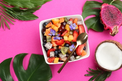 Flat lay composition with delicious exotic fruit salad on pink background