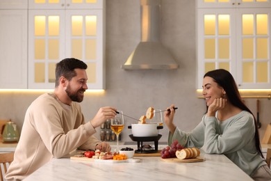 Photo of Affectionate couple enjoying fondue during romantic date in kitchen