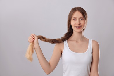 Photo of Teenage girl with strong healthy braided hair on light grey background
