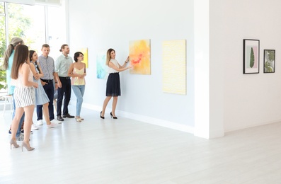 Group of people with guide at exhibition in art gallery