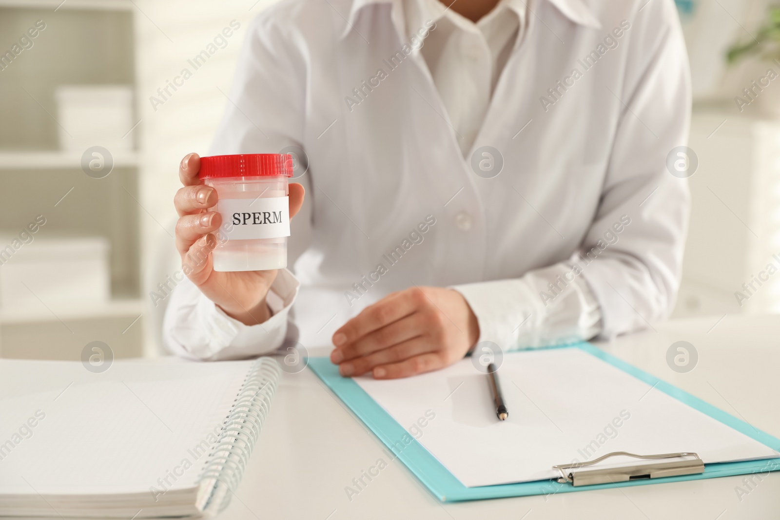 Photo of Doctor holding container with sperm in hospital, closeup