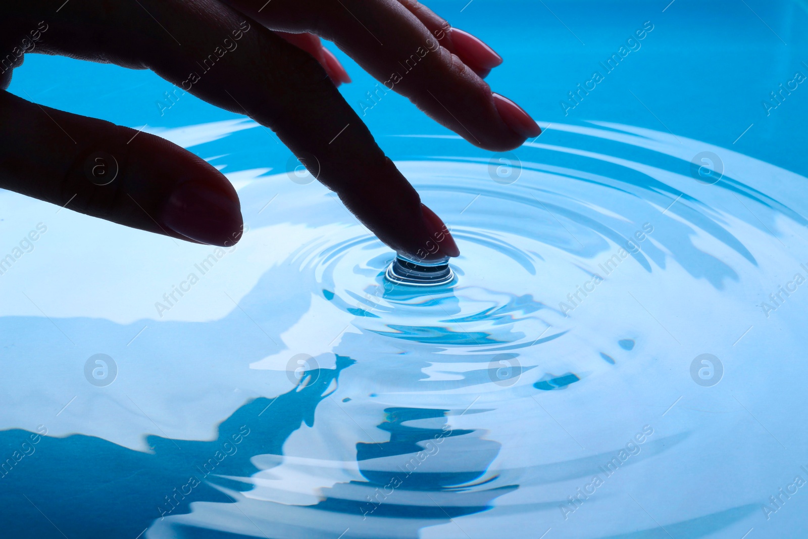 Photo of Woman touching clear water, closeup. Making ripples