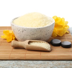 Natural sea salt in bowl, flowers, spa stones and scoop on wooden table against white background