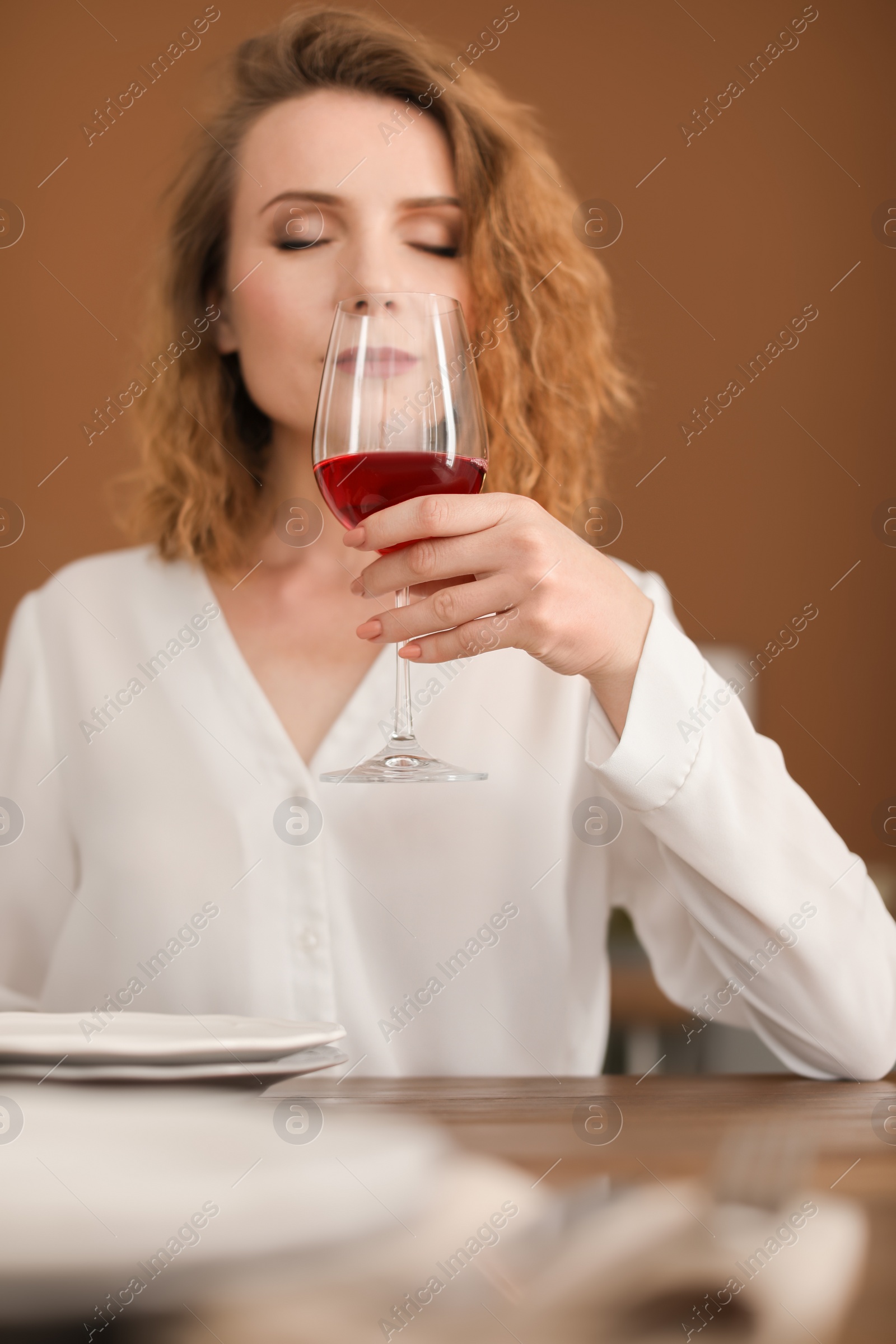 Photo of Woman with glass of wine at table in restaurant