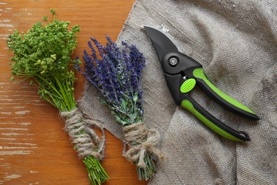 Photo of Secateur, lavender and wild flowers on wooden table, flat lay