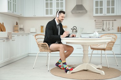 Businessman in underwear pretending to wear formal clothes during video call at home