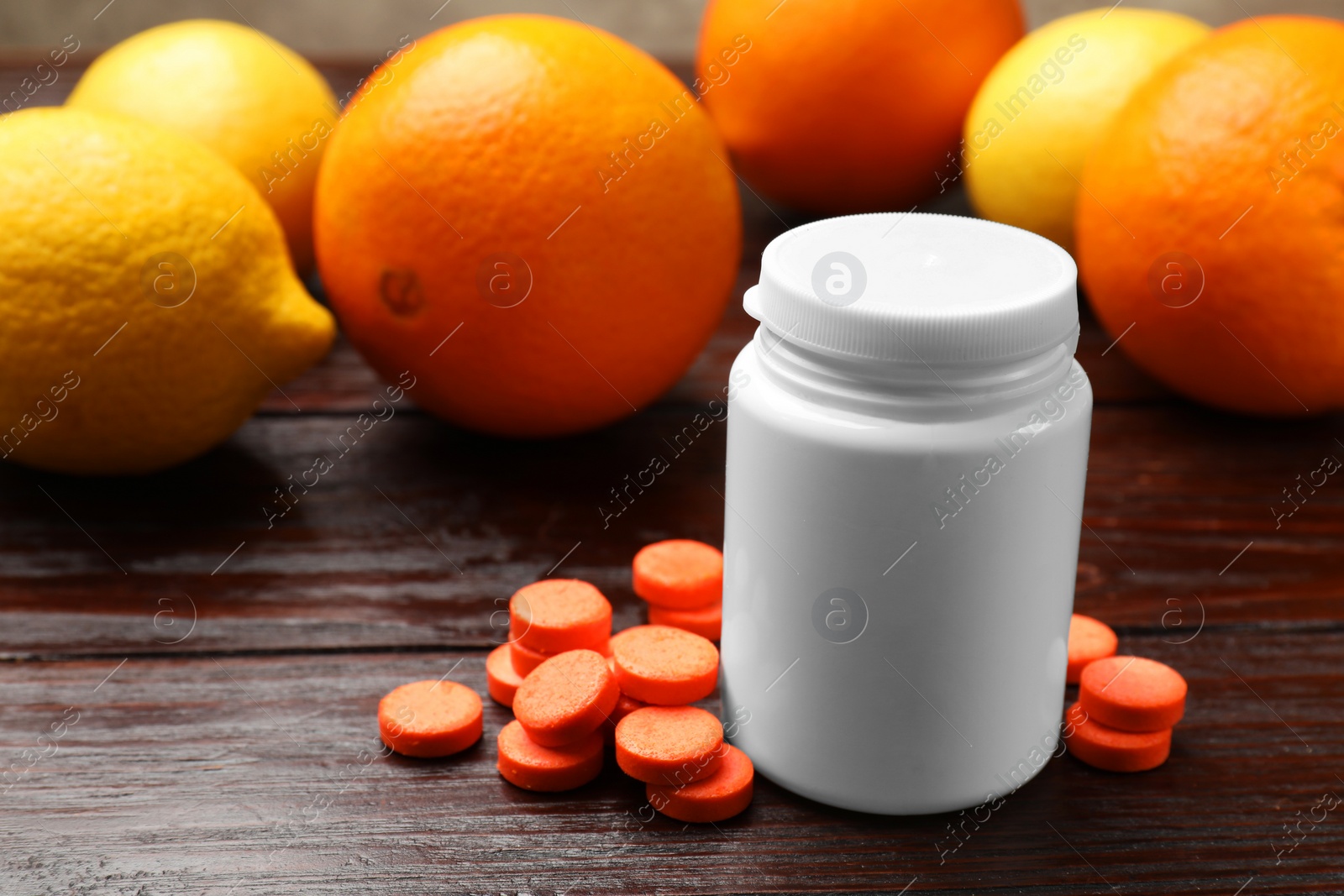 Photo of Dietary supplements. Plastic bottle, pills and fruits on wooden table, closeup