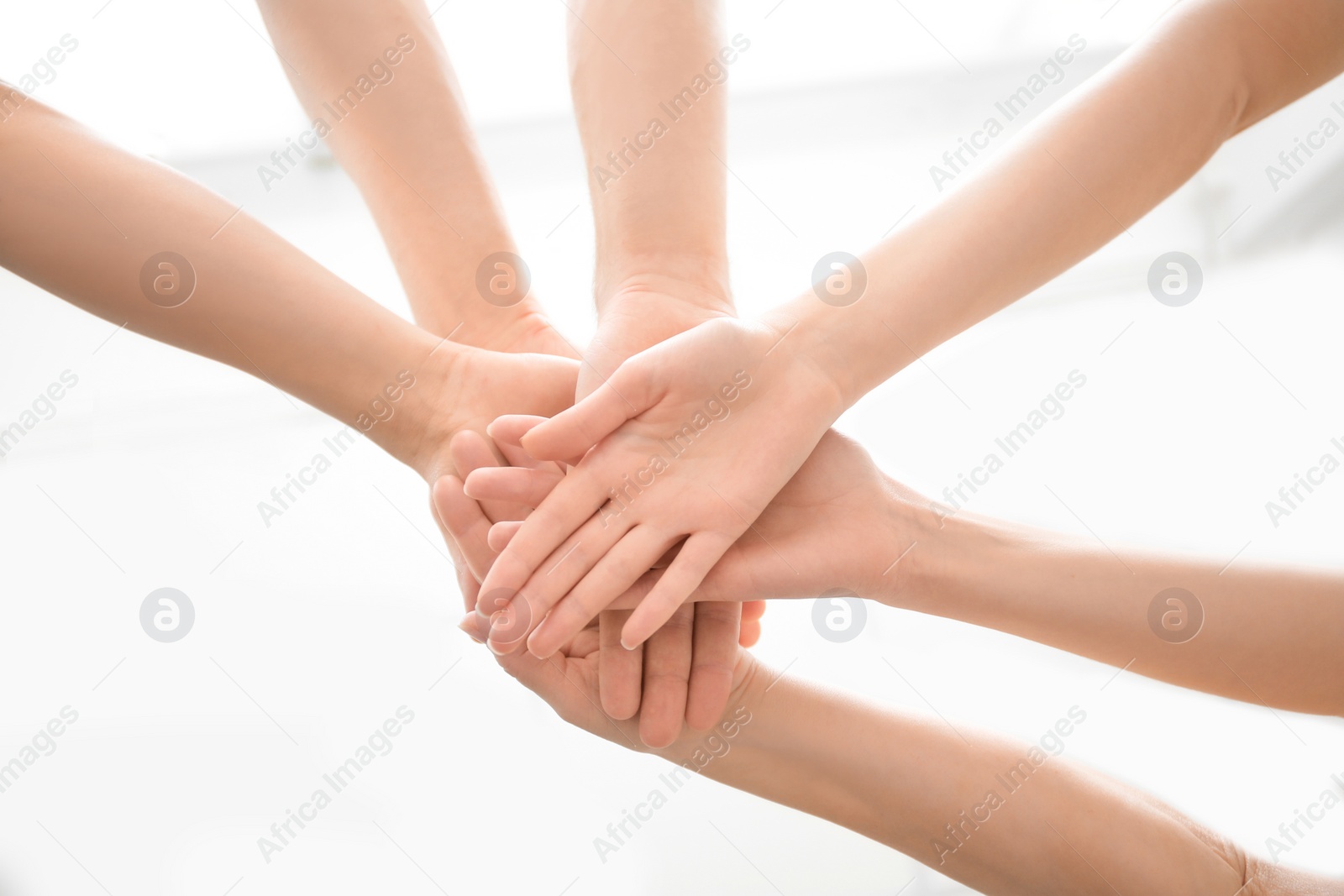 Photo of People putting hands together on light background, closeup. Unity concept