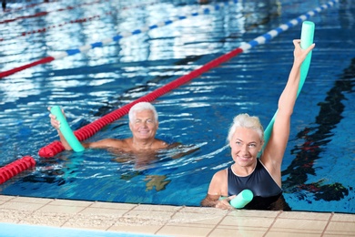 Photo of Sportive senior couple doing exercises in indoor swimming pool