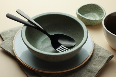 Stylish empty dishware and cutlery on beige background, closeup