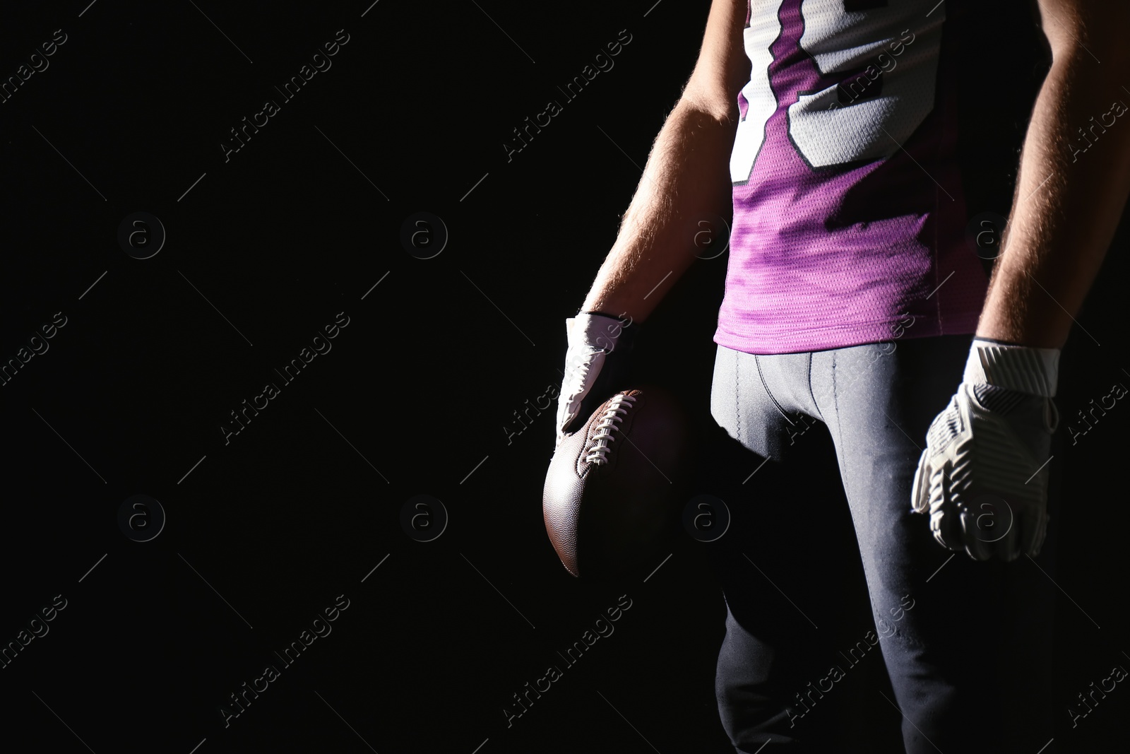 Photo of American football player with ball on dark background, closeup. Space for text