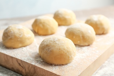 Photo of Fresh raw dough with flour on wooden board