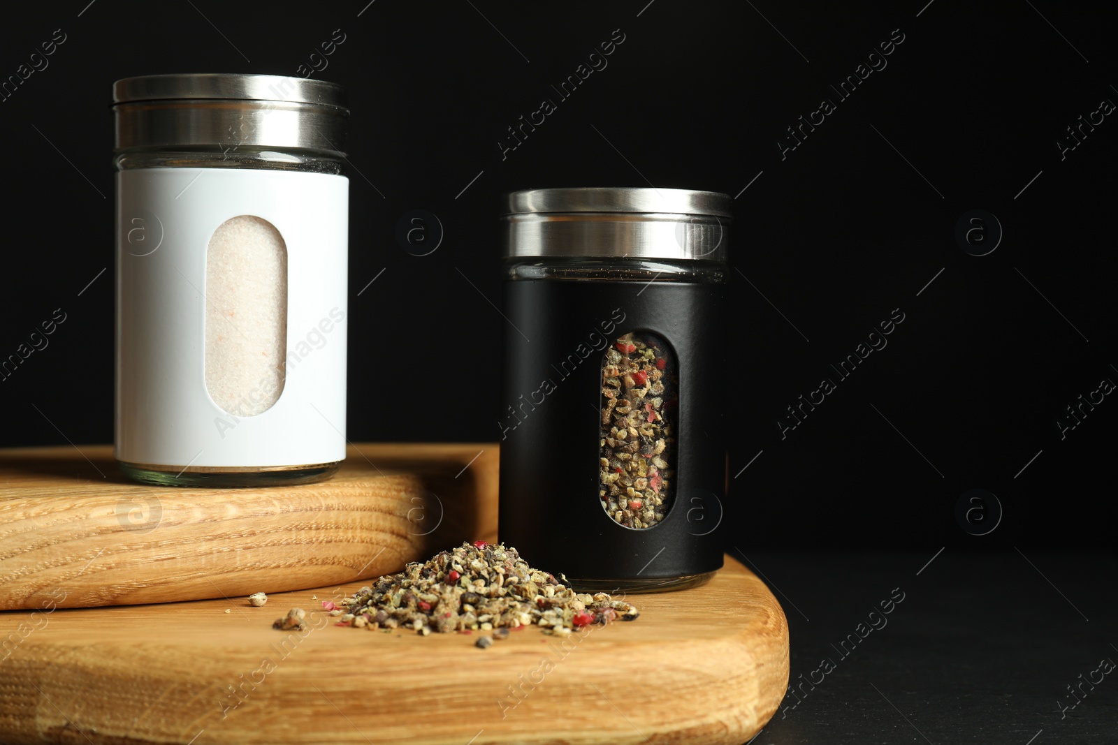 Photo of Salt and pepper shakers on table against black background