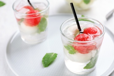 Glasses with tasty melon and watermelon ball drinks on plate, closeup