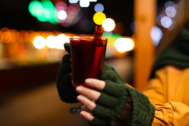 Photo of Woman with tasty mulled wine at winter fair, closeup