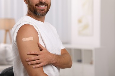 Photo of Man with sticking plaster on arm after vaccination at home, closeup. Space for text