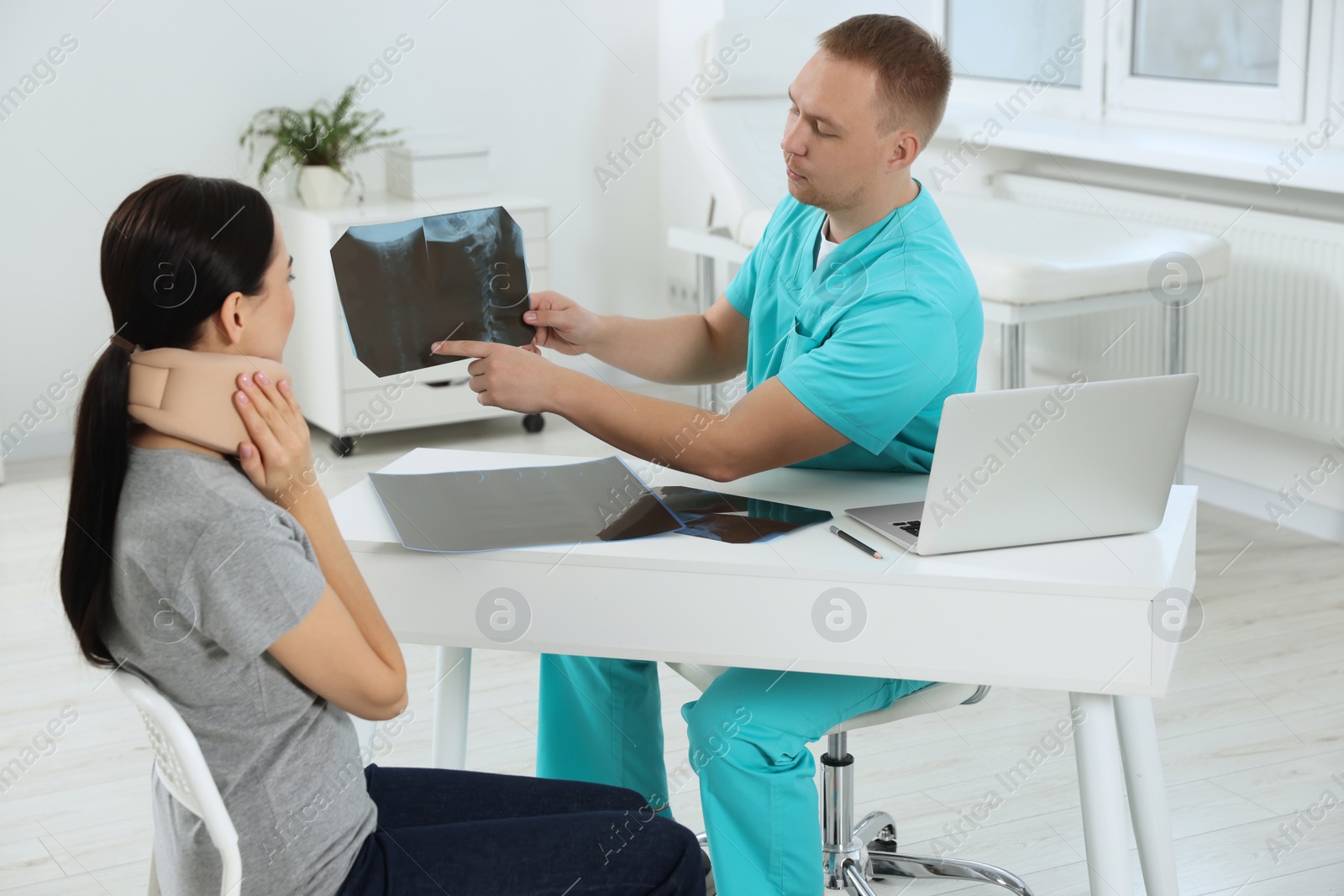 Photo of Doctor with neck MRI image consulting patient in clinic