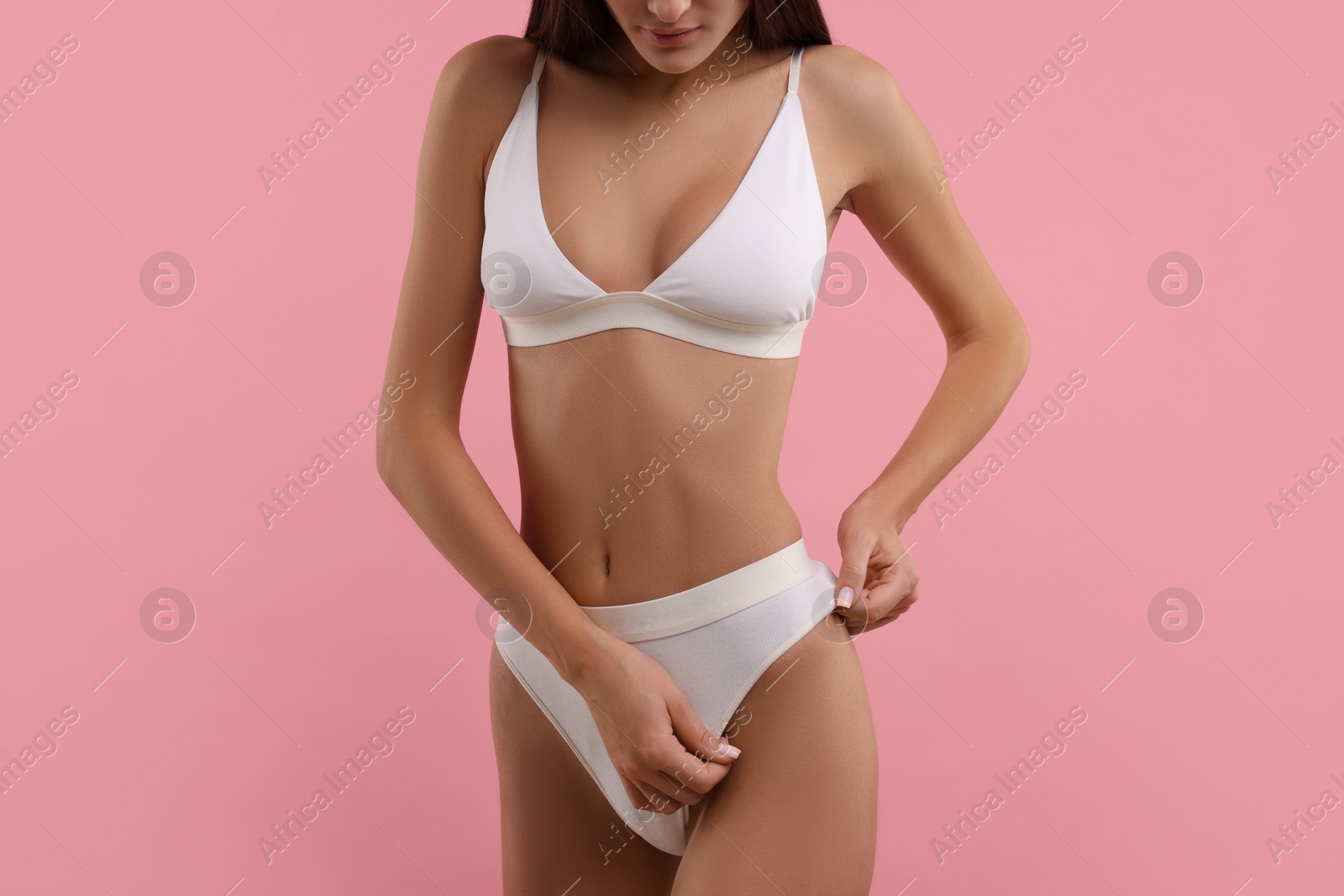 Photo of Young woman in stylish white bikini on pink background, closeup