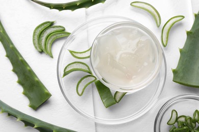 Photo of Aloe vera gel and slices of plant on white background, flat lay