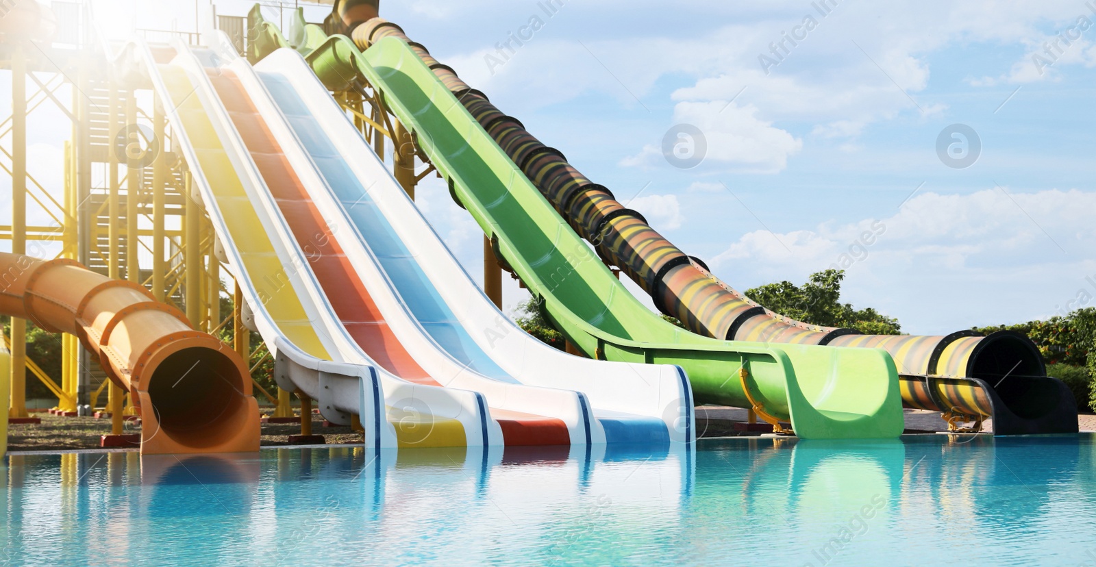 Image of Beautiful view of water park with colorful slides and swimming pool on sunny day 