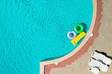 Inflatable rings and mattress floating in swimming pool, top view with space for text. Summer vacation