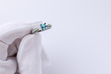 Photo of Jeweler holding topaz ring on white background, closeup. Space for text