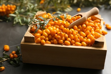 Photo of Fresh ripe sea buckthorn in wooden crate on grey table, closeup