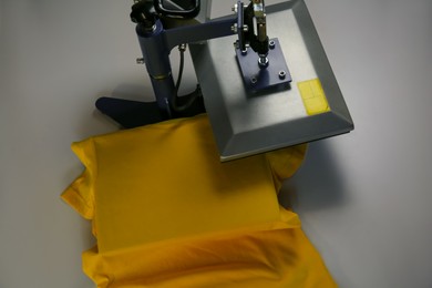 Photo of Printing logo. Heat press with t-shirt on white table, above view