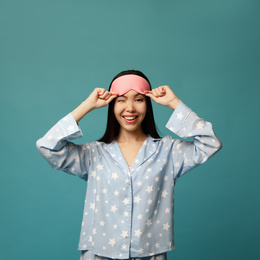 Photo of Beautiful Asian woman wearing pajamas and sleeping mask on blue background. Bedtime
