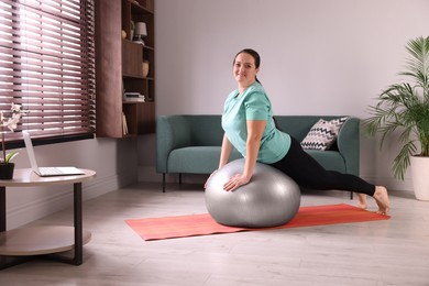 Photo of Overweight woman doing exercise with fitness ball at home