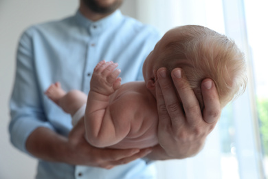 Photo of Father holding his newborn baby at home, closeup