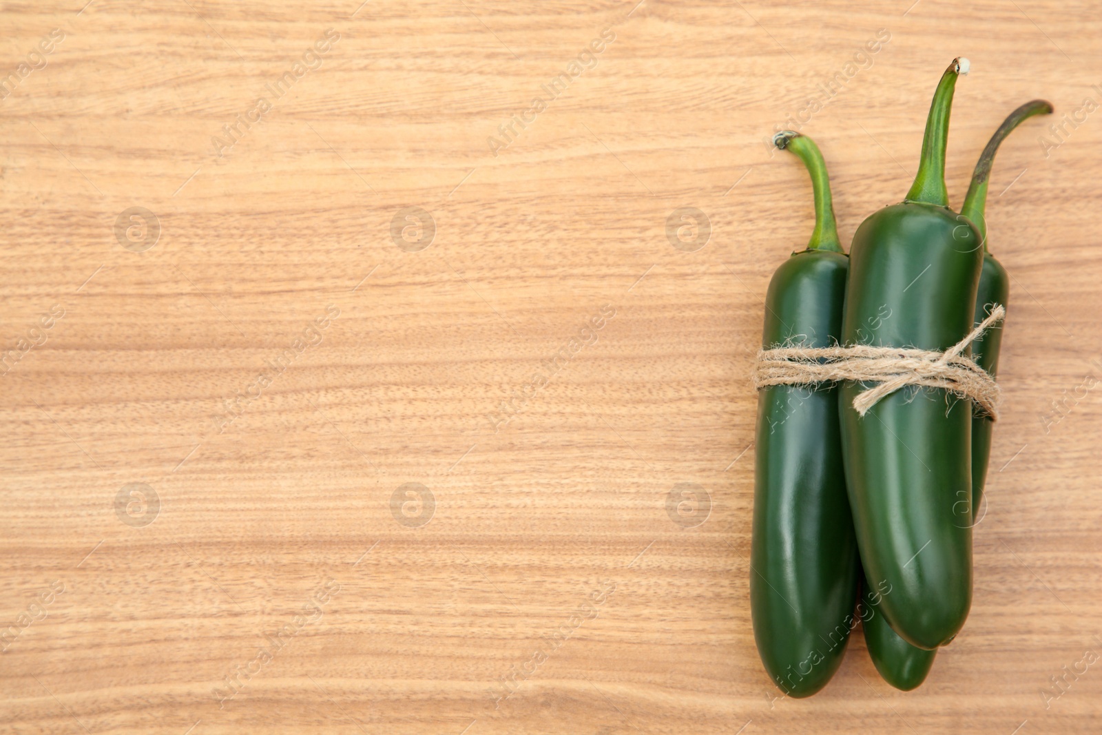 Photo of Fresh ripe green jalapeno peppers on wooden table, top view. Space for text