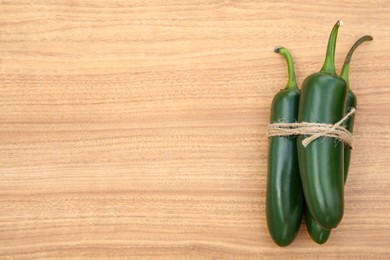 Photo of Fresh ripe green jalapeno peppers on wooden table, top view. Space for text