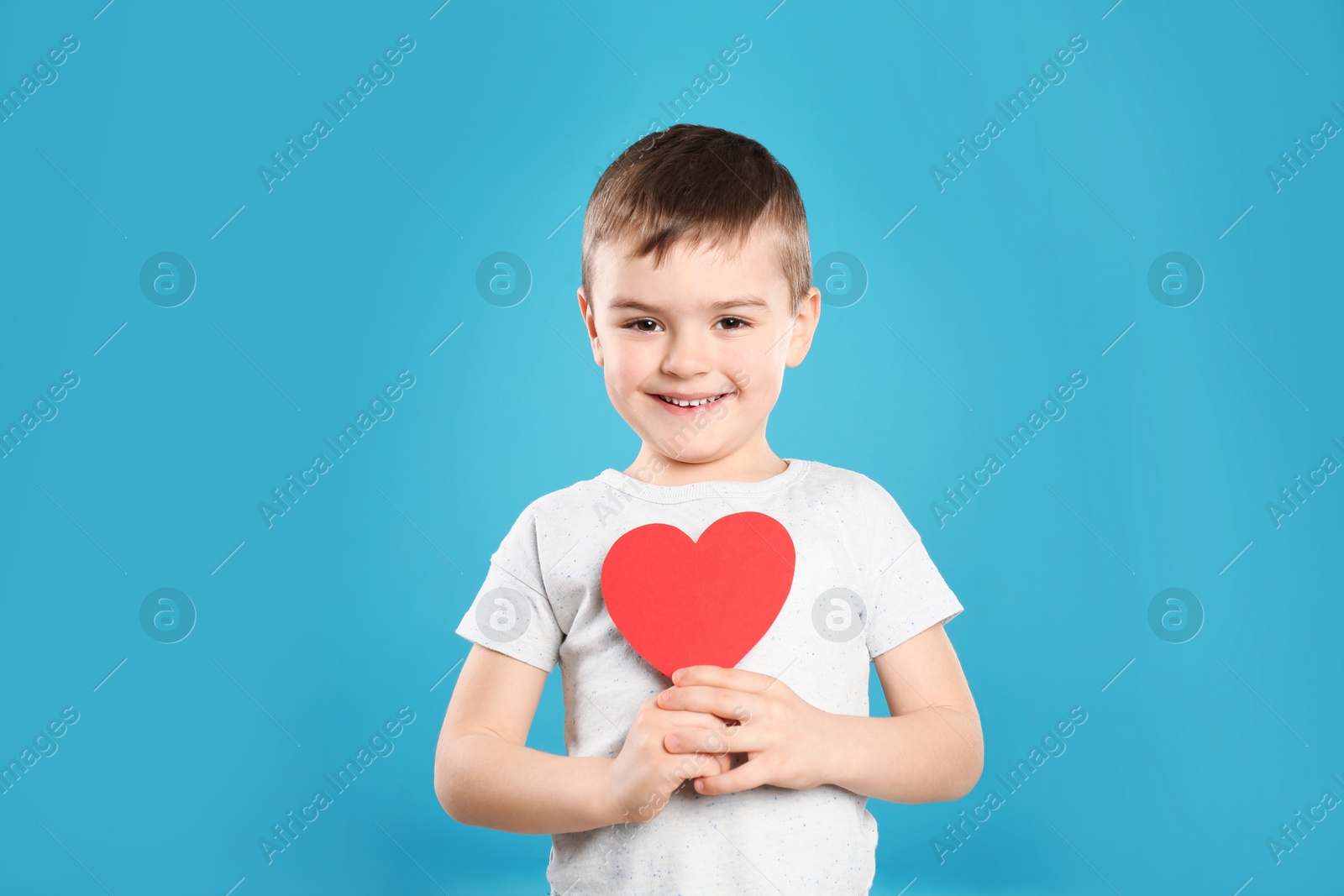 Photo of Portrait of boy with paper heart on color background