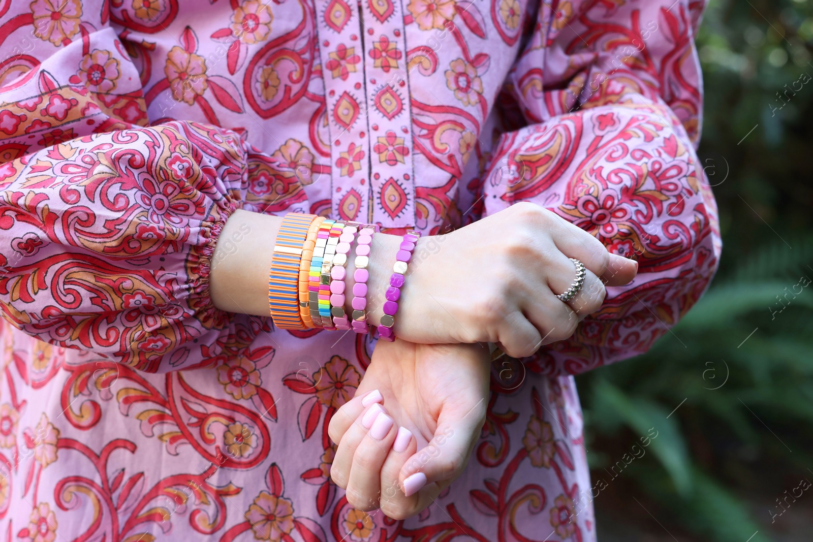 Photo of Woman wearing many stylish bracelets outdoors, closeup