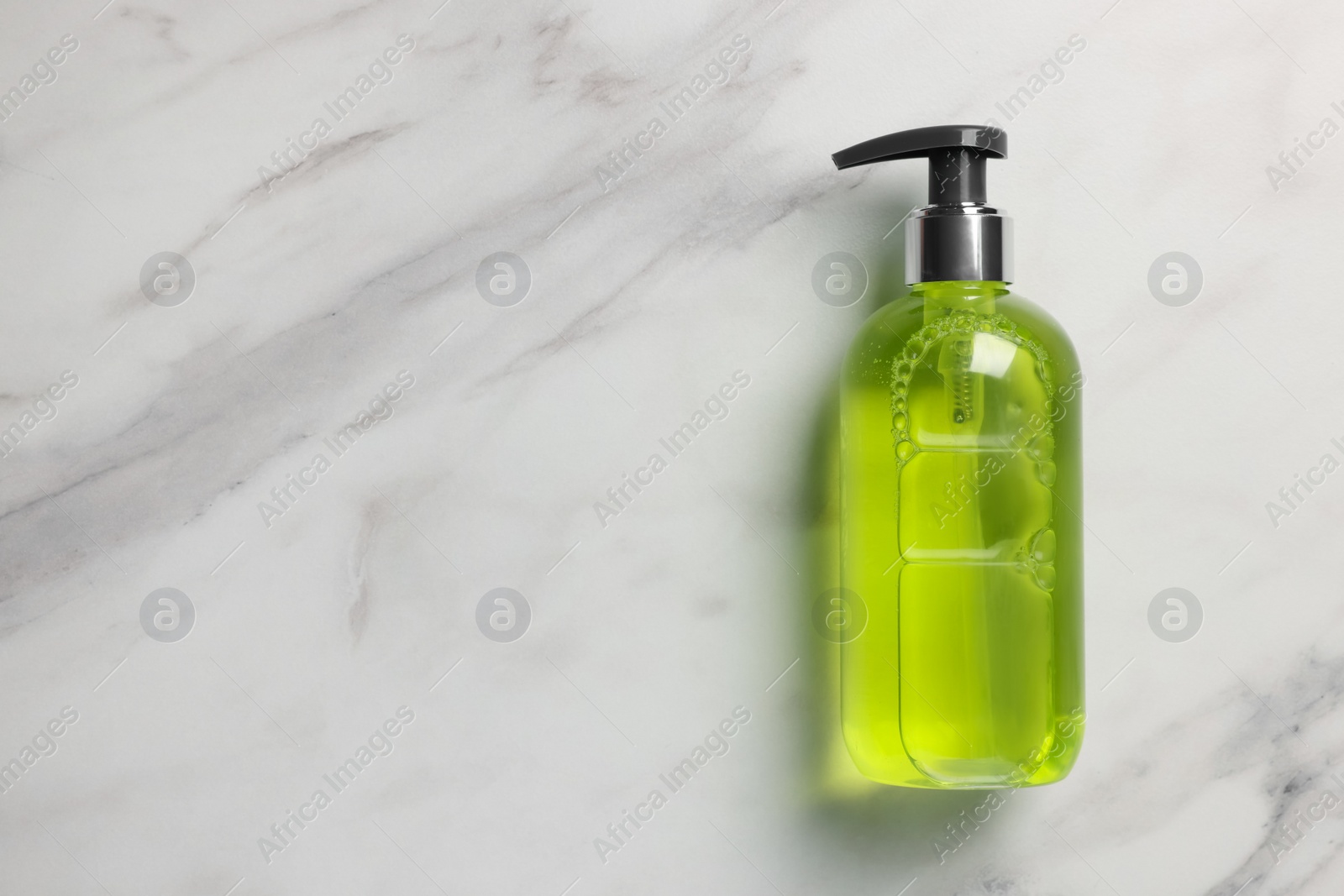 Photo of Dispenser of liquid soap on white marble table, top view. Space for text