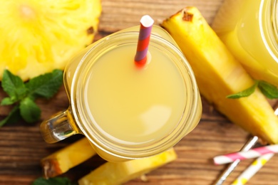 Photo of Delicious pineapple juice and fresh fruit on wooden table, flat lay