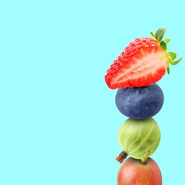 Stack of different fresh tasty berries on cyan background, space for text