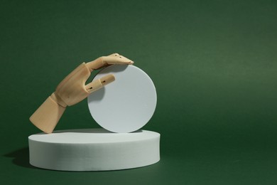 Photo of Product photography props. Round shaped podiums and wooden mannequin hand on green background, space for text