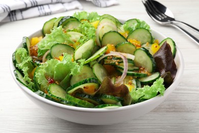 Photo of Bowl of delicious cucumber salad on white wooden table, closeup