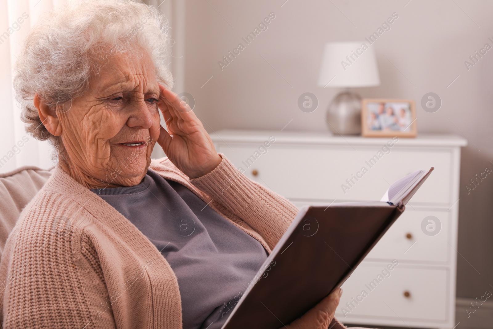 Photo of Senior woman with notebook at home. Age-related memory impairment