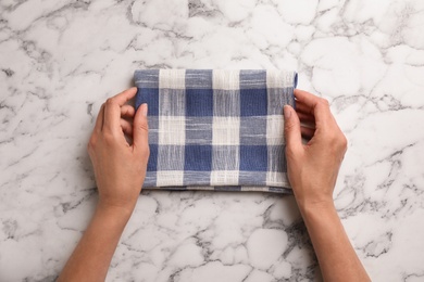 Woman with checkered kitchen towel on marble background, top view