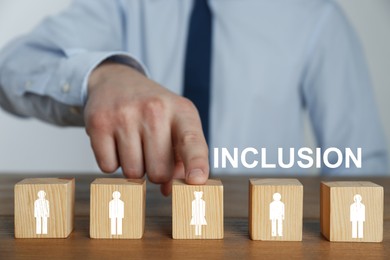 Image of Concept of DEI - Diversity, Equality, Inclusion. Businessman and wooden cubes with images of people on table, closeup