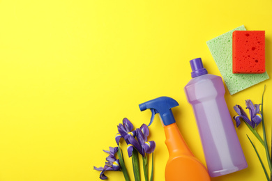 Photo of Composition with spring flowers and cleaning supplies on yellow background, flat lay. Space for text